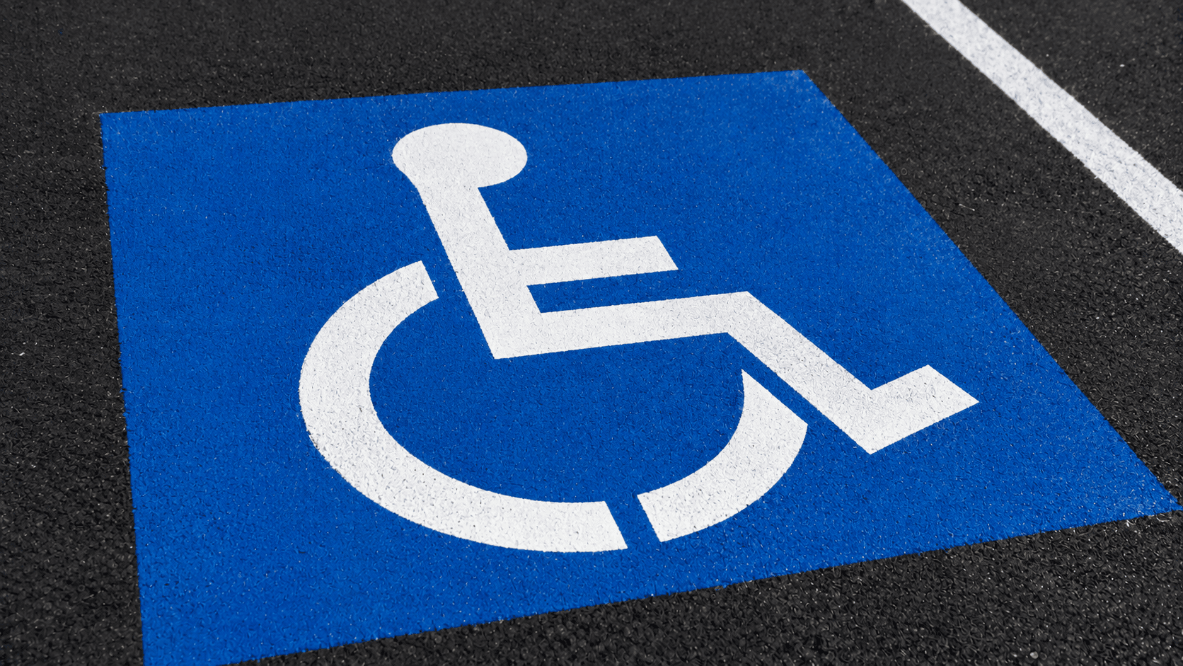 Close-up of the blue International Symbol of Accessibility painted on a parking stall