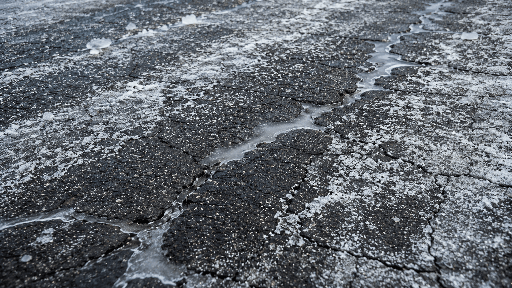 Salt residue and freeze-thaw cracking on a Northeast commercial parking lot